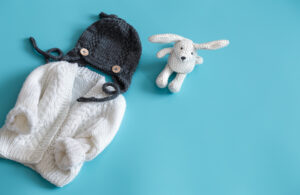 Knitted baby clothes and accessories on a blue background . Product 2